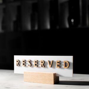 A 'Reserved' sign on a table in a stylish, dimly lit restaurant interior.